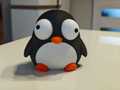 Pinguin Goofy Series - vedere frontală cu ambii ochi mobili pe masă albă