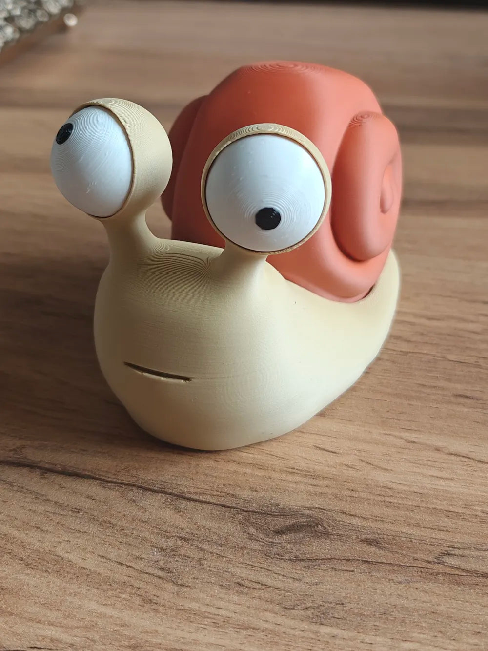 Melc Goofy Series - vedere frontală cu ambii ochi mobili pe antene pe masă din lemn