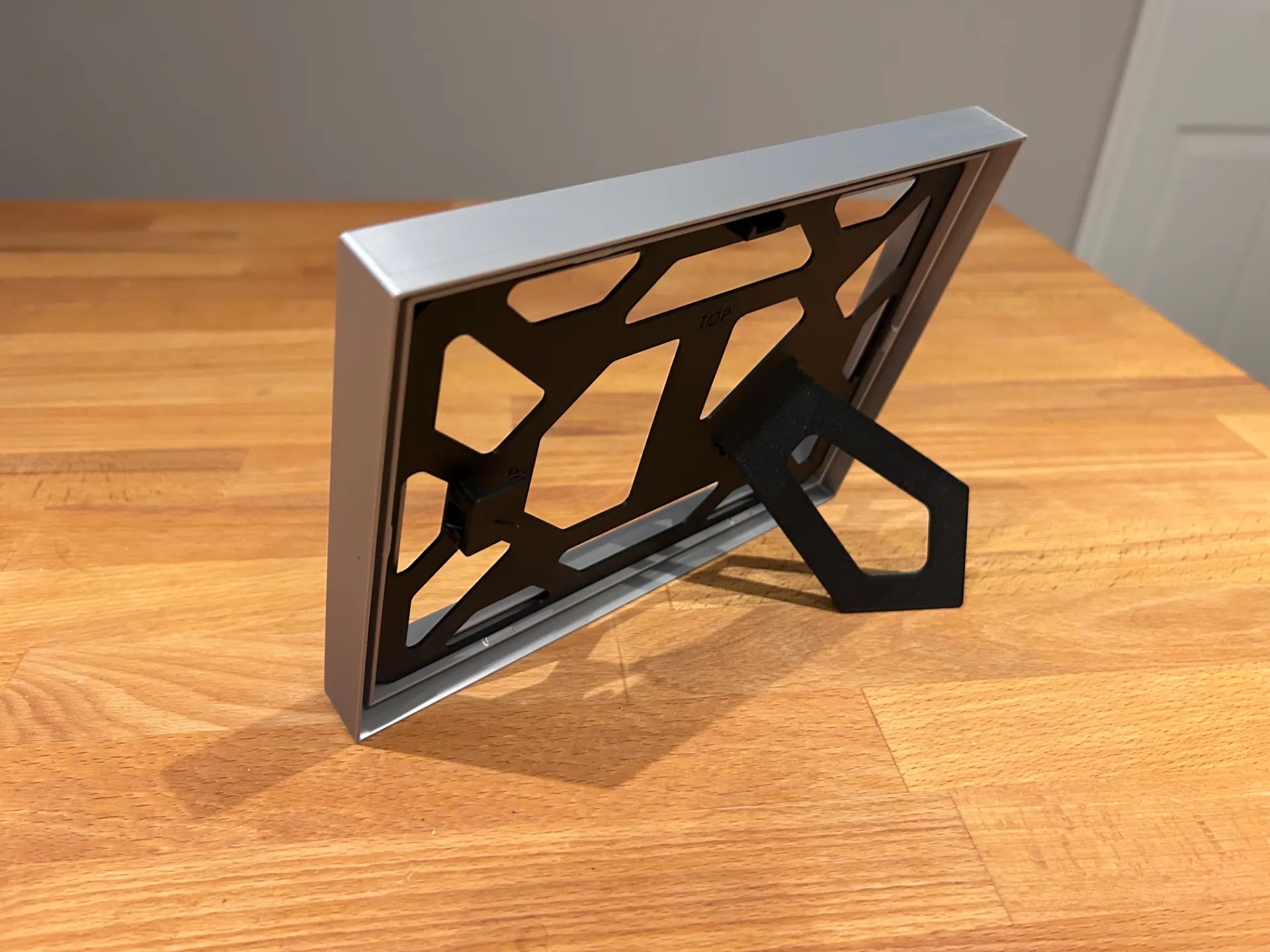 Ramă foto A4 imprimată 3D – vedere orizontală cu suport rabatabil, design geometric negru