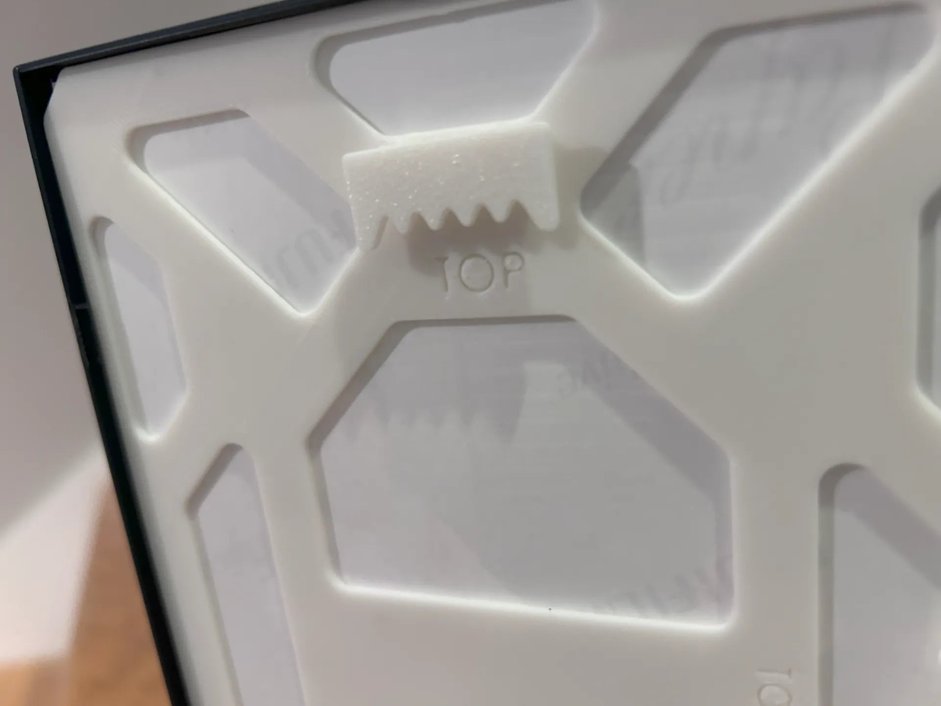 Ramă foto A4 – detaliu spate cu design geometric hexagonal și mecanism suport imprimat 3D alb
