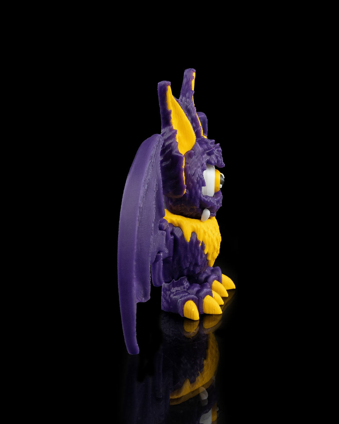 That-looks-bat figurina liliac monstru violet cu accente galbene, vedere laterala stanga, fundal negru